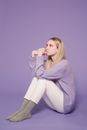 Dreamy woman with colorful makeup sitting alone in studio