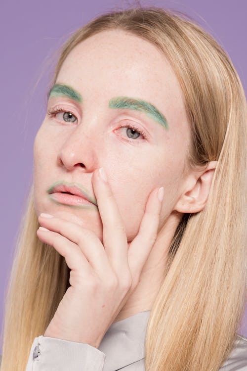 Thoughtful woman with colorful makeup in studio