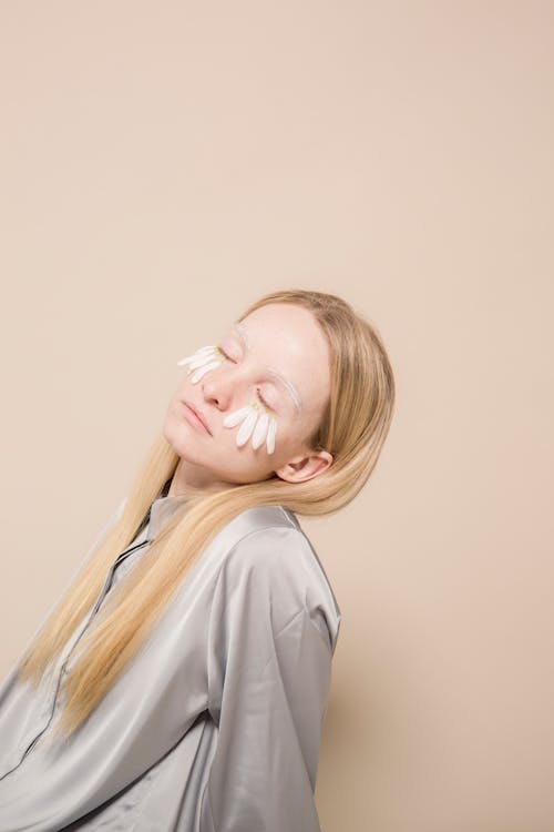 Dreamy woman with white petals on face in studio