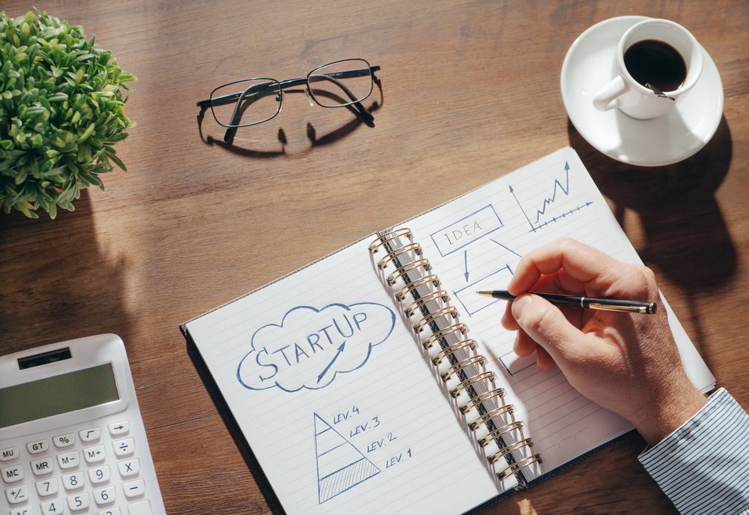 Creatieve werkplek met notitieblok voor startersplanning, bril en een kop koffie