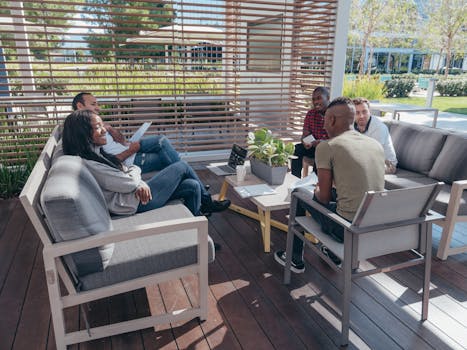 Diverse team having a collaborative meeting outdoors in a modern office setting.