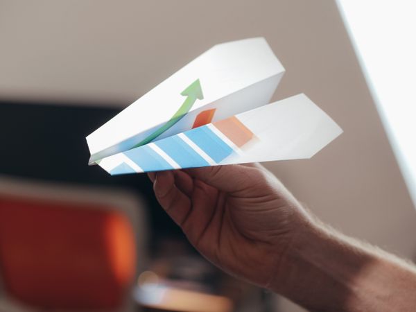 Hand holding a paper plane folded from a printed chart — photo by Kindel Media on Pexels