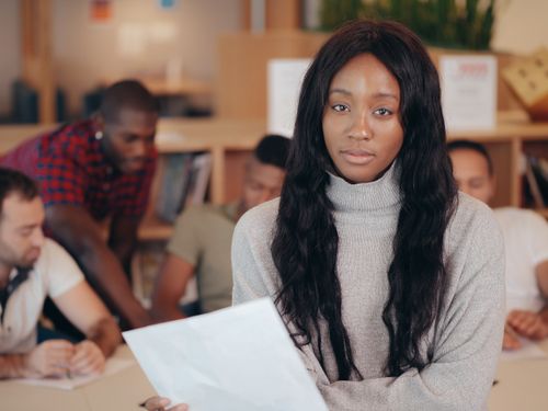 Free Female team member holding documents in a diverse office meeting. Stock Photo