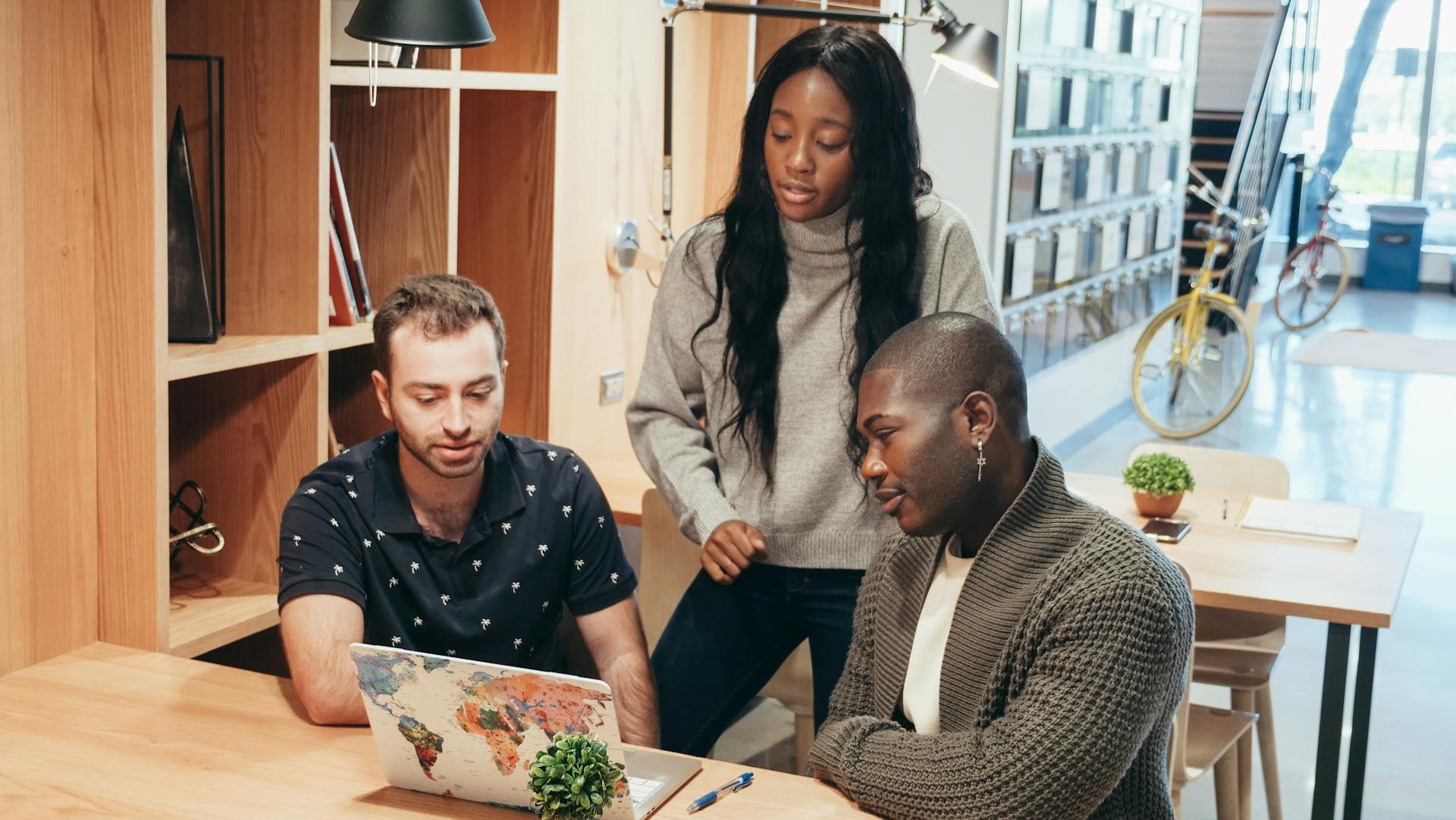 A diverse team discussing ideas around a laptop in a contemporary office setting.