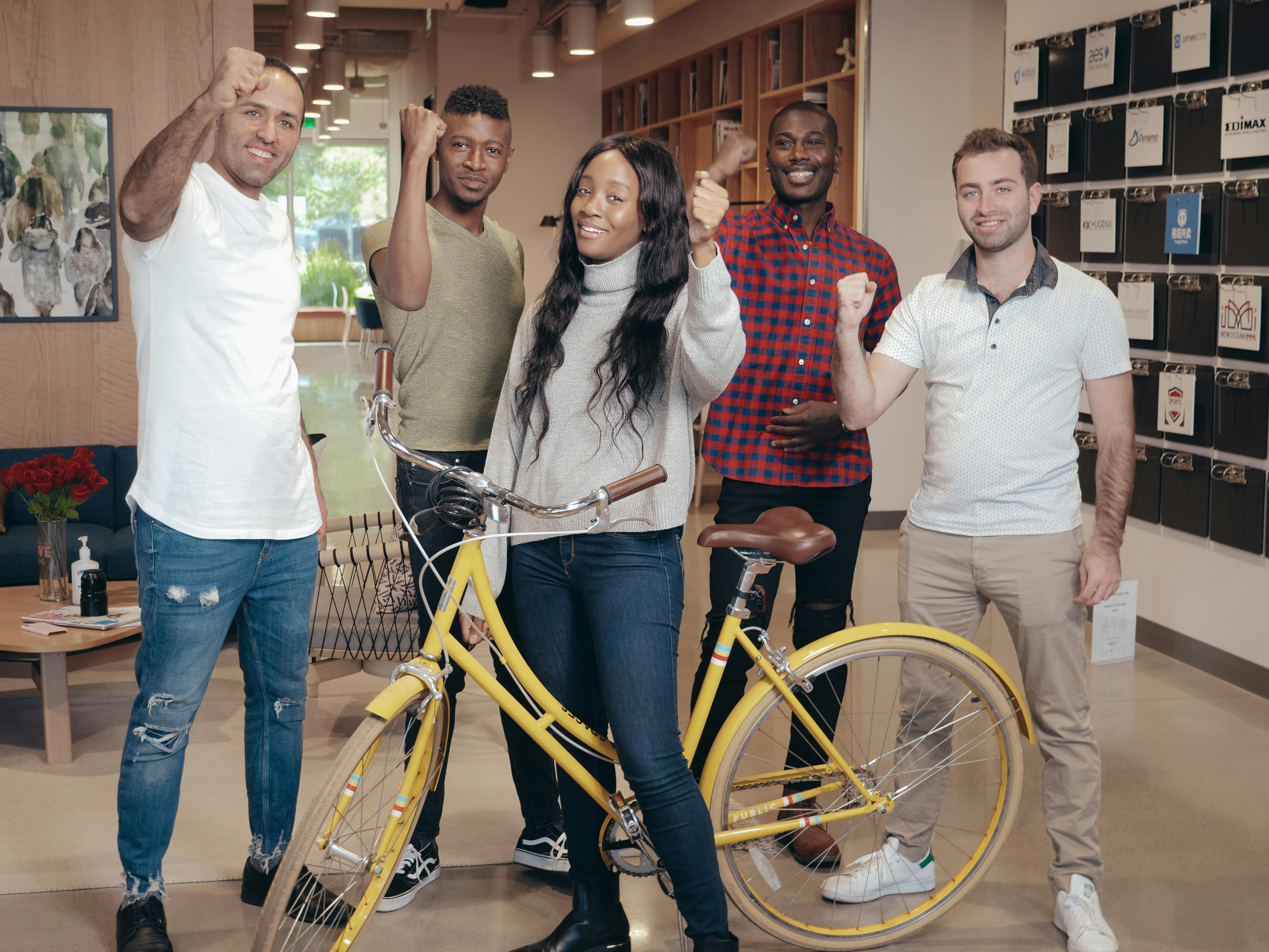 3 women standing beside blue bicycle