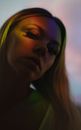 Low angle of charming young female with long blond hair illuminated with shiny light and looking at camera
