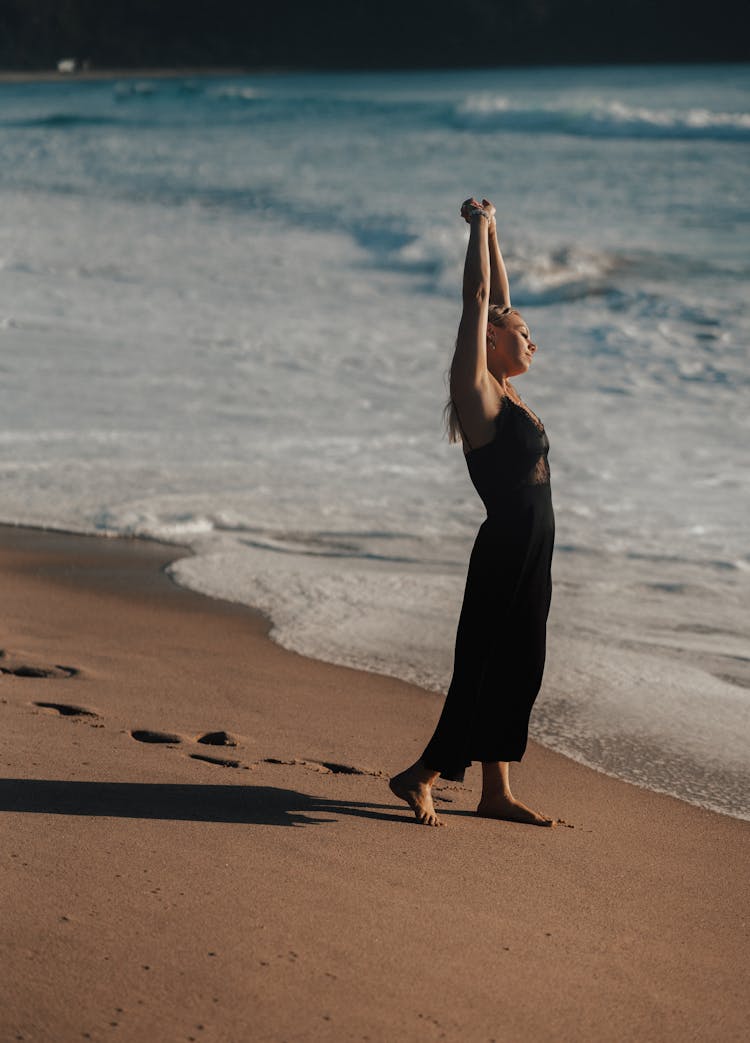 Young Woman With Raised Arms On Beach