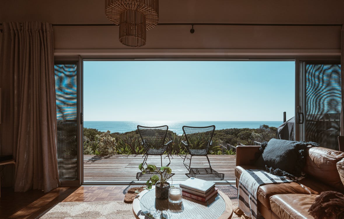 Free Interior design of luxurious apartment with large balcony doors and wooden terrace having picturesque view on green forested seashore and calm blue sea Stock Photo