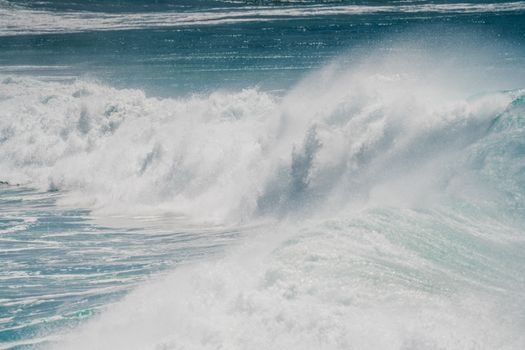 Captivating image of powerful ocean waves crashing under a clear blue sky, showcasing nature's force.