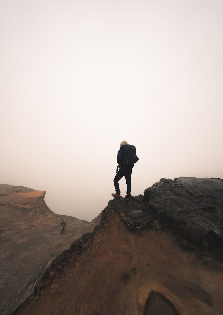 Backpacker Standing At The Edge Of A Cliff