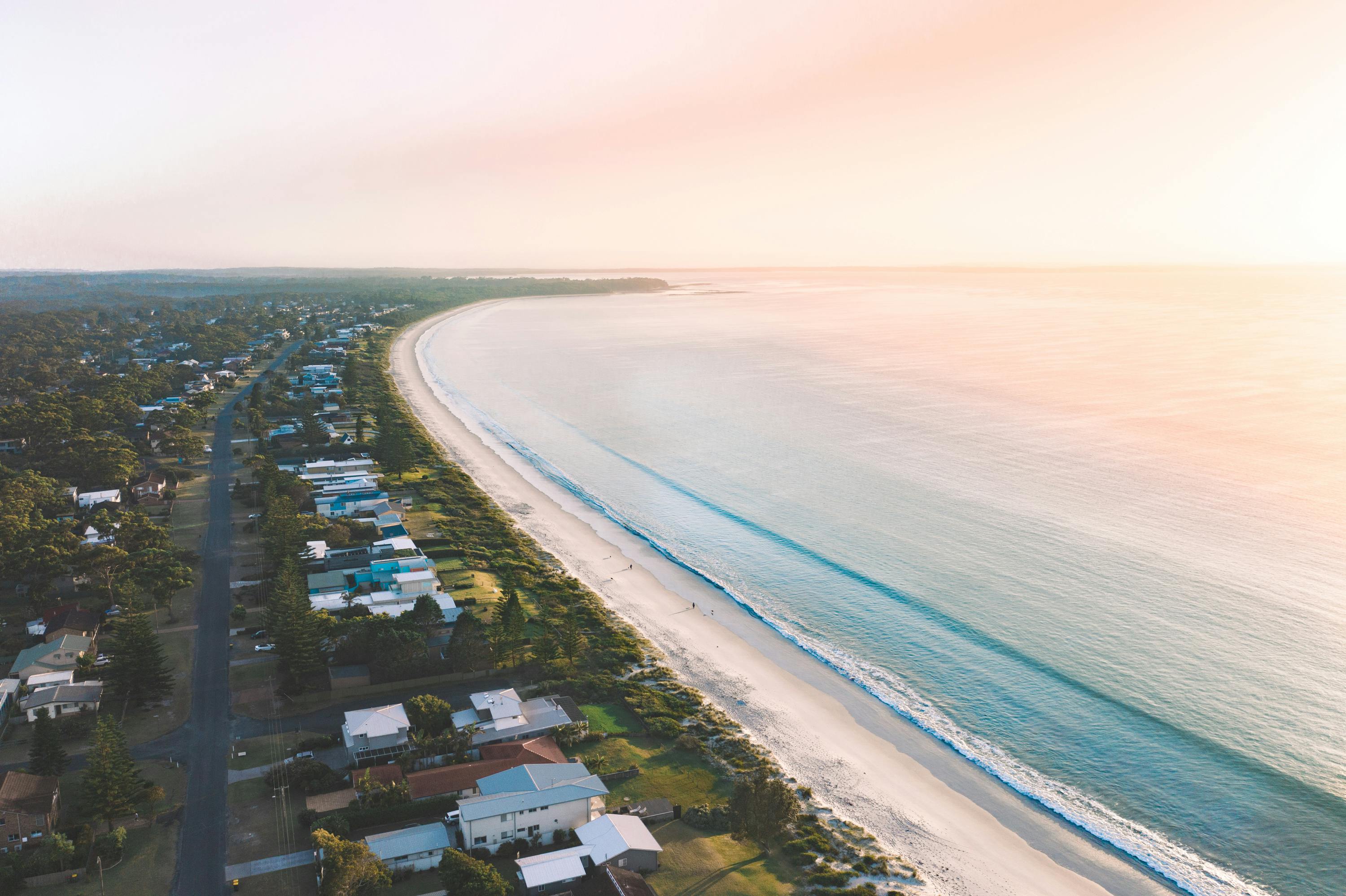 Aerial view of a peaceful Australian coastal town and long beach; seeking new, healthy environments assists in dealing with cravings successfully.