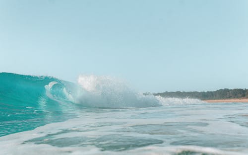 Wavy foamy ocean near shore under blue sky