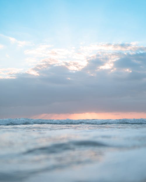 Wavy rippling ocean water under blue cloudy sky in summer day at sunset