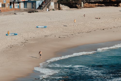 Faceless man walking on beach near sea