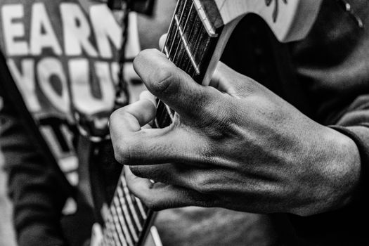 A black and white close-up of a musician's hand playing an electric guitar.. black, white, close