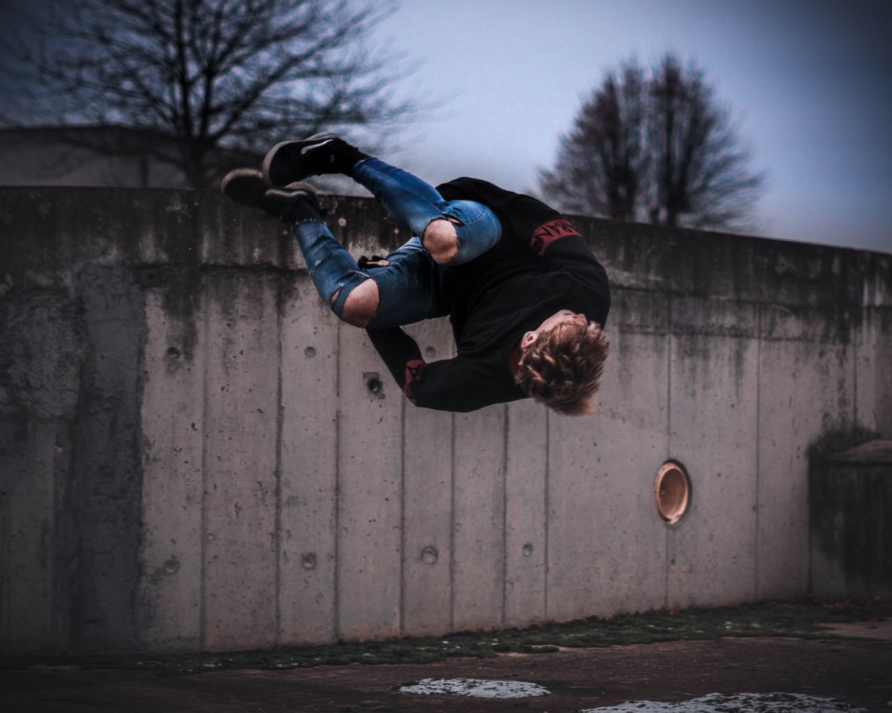 a skilled parkour athlete performing a midair side flip against a conc