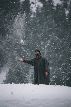 A man having fun playing with snow during a snowy winter day in the forest.