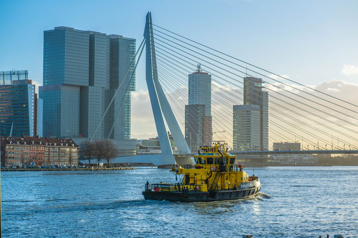 The white pylon of the Erasmus Bridge and the Wilhelminapier towers above a Port of Rotterdam patrol boat on the Nieuwe Maas