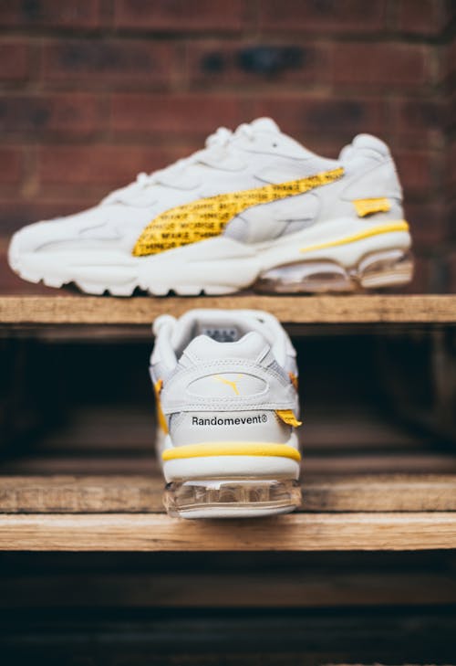 White and Yellow Rubber Shoes on a Wooden Surface