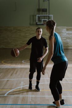 Two women engaging in a basketball game on an indoor court, focused on practice.