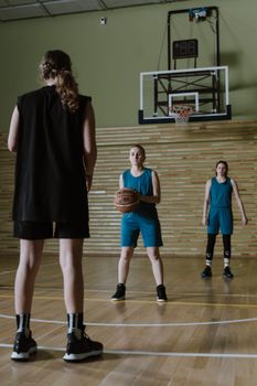 Three women playing basketball indoors on a court, preparing for a game.