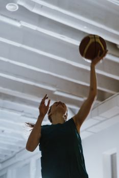 A woman skillfully reaching for the basketball during an indoor game, showcasing agility and coordination.
