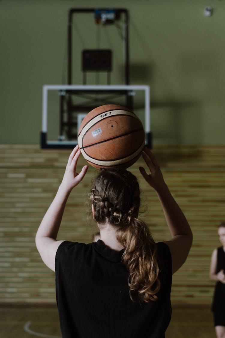 A Person Holding A Basketball Ball On Her Head