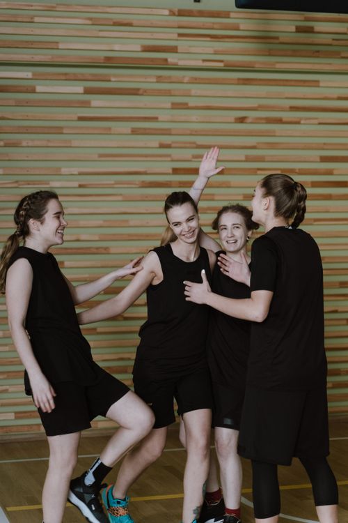 Free Four young women basketball players share a joyful moment indoors, celebrating teamwork and friendship. Stock Photo