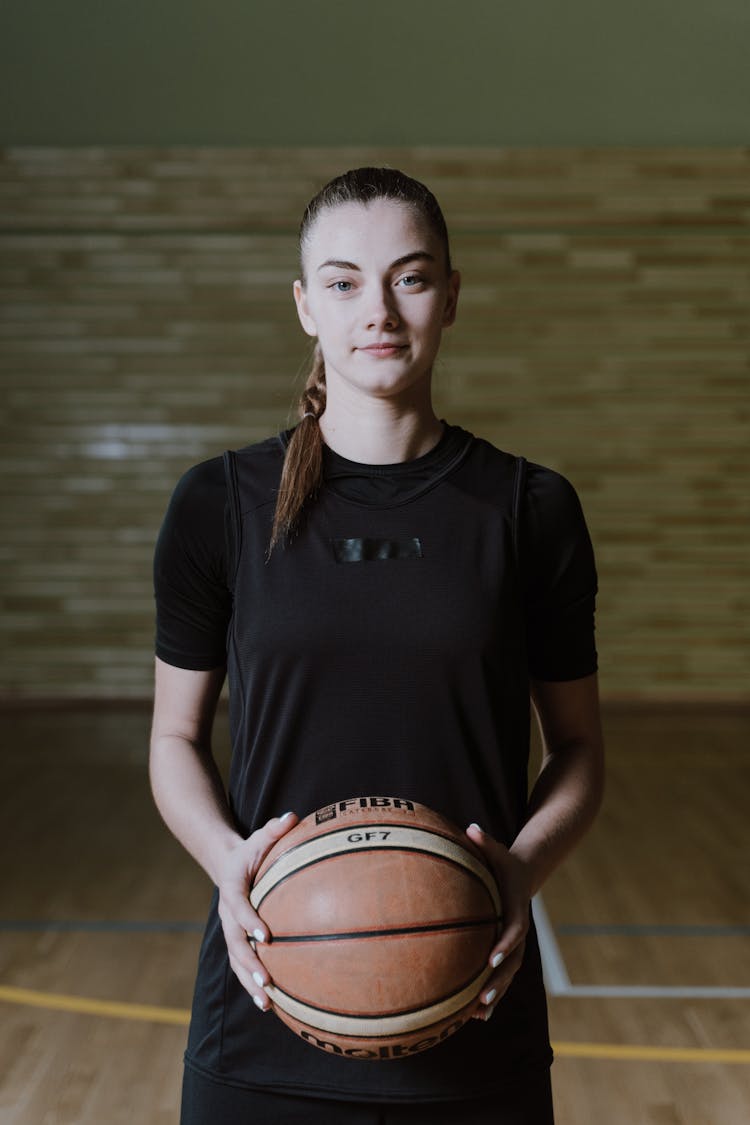 Woman In Black Shirt Holding Brown And White Basketball Ball