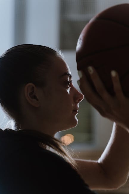 Side profile of young woman holding a basketball, with a focused expression.