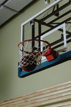 Basketball scoring a perfect shot through the hoop on an indoor court. Dynamic close-up capture.