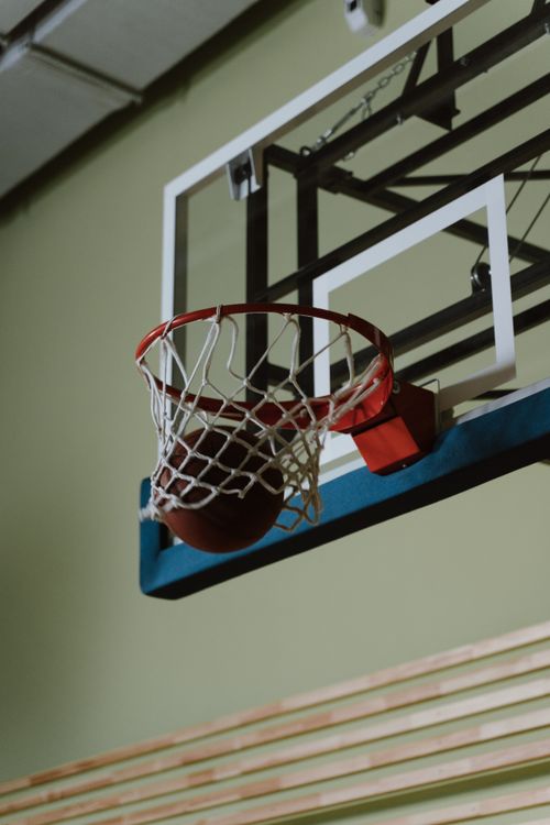 Free Basketball scoring a perfect shot through the hoop on an indoor court. Dynamic close-up capture. Stock Photo