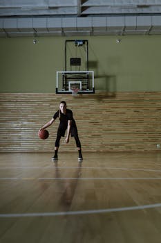 Woman dribbles basketball on indoor court. Perfect for sports or training themes.