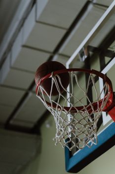 Close-up of a basketball going through a hoop with a net, symbolizing success and sportsmanship.