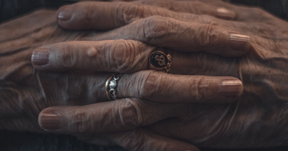 Close-up of an older adult's hands, showing finger joints, resting on a table