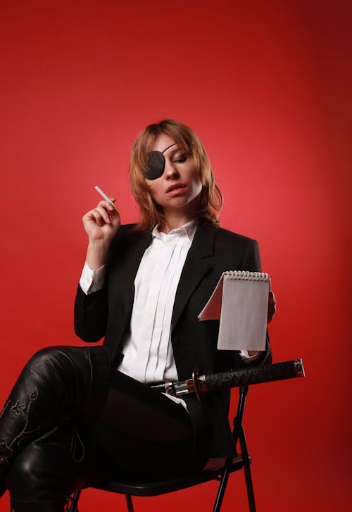 Well dressed model with cigarette and notepad on red background