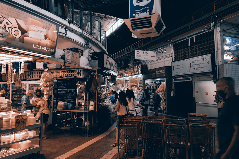 Vibrant indoor market filled with shoppers, food stalls, and lighting. Captures urban market vibe.