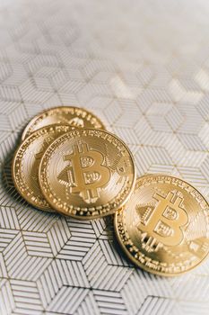 Close-up of gold Bitcoin coins on a patterned surface, representing digital currency.