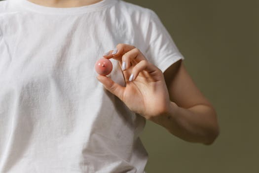Close-up of a person in a white t-shirt holding a small pink object.