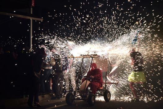 Exciting nighttime fireworks display with people gathered around a go-kart, celebrating outdoors.