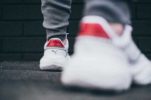 Free Person Wearing a Red and White Puma Sneakers Stock Photo