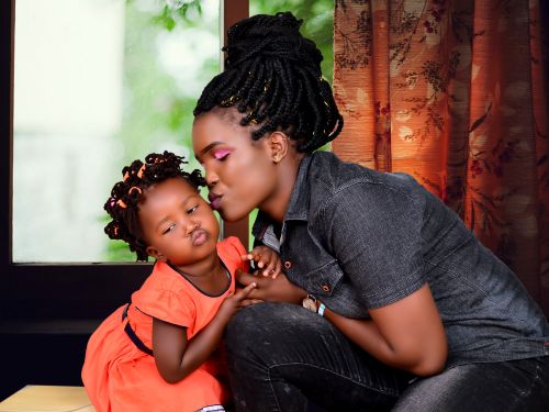 Free A mother kisses her daughter tenderly indoors, highlighting familial love and connection. Stock Photo