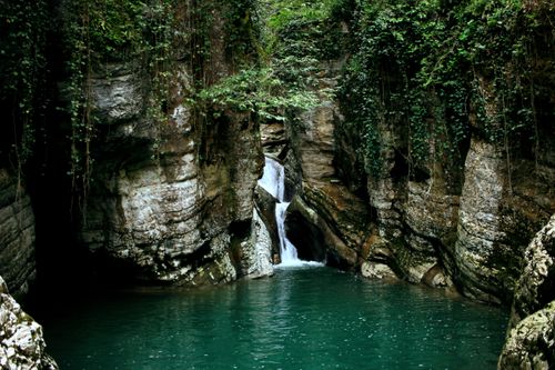 Free Serene waterfall flowing between lush, rocky cliffs in a pristine natural paradise. Stock Photo