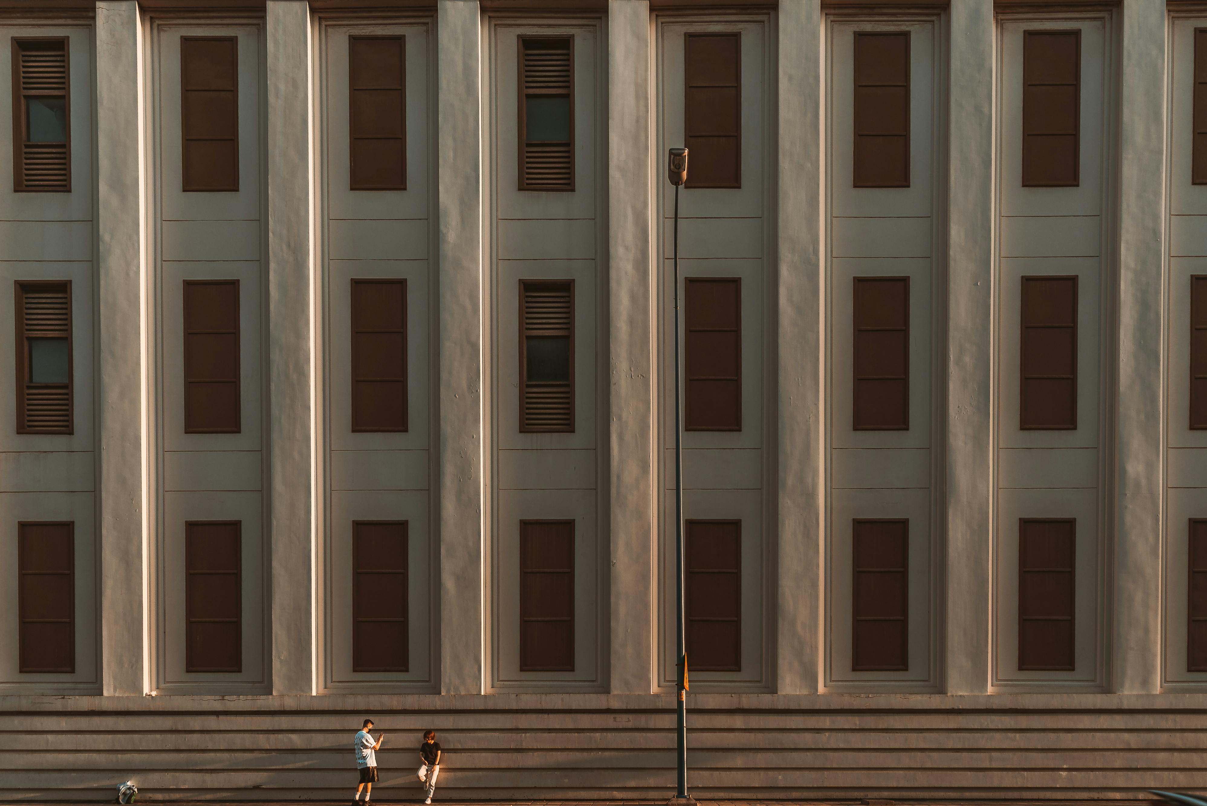 Symmetrical facade of a modern building with two people and a dog."