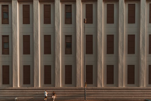 Symmetrical facade of a modern building with two people and a dog."