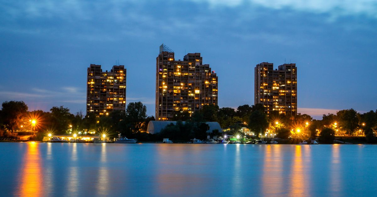 Beautiful twilight cityscape with illuminated skyscrapers reflecting on the waterfront.
