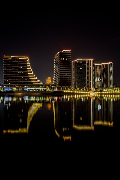 Free Illuminated Skyscrapers Reflecting in Water at Night Stock Photo