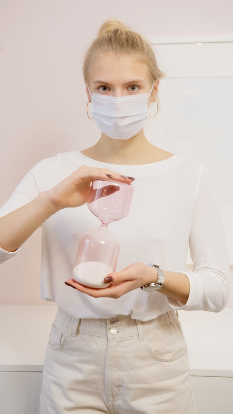 Woman In Facemask Holding Hourglass