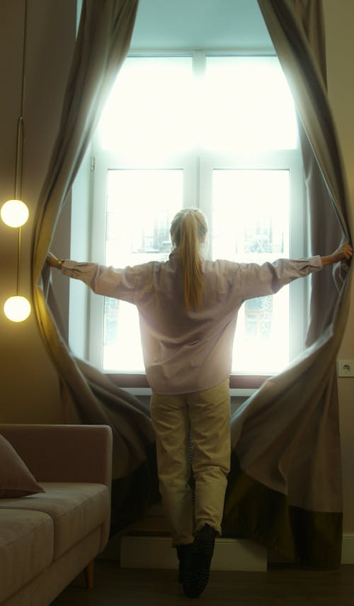 A Woman Opening Curtains