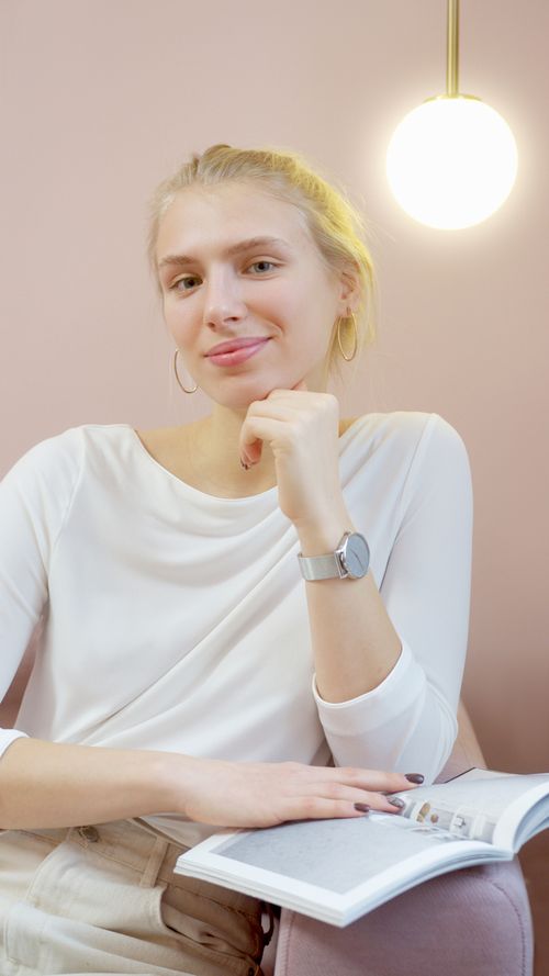 Free Woman in a white top posing with a book under a warm lamp indoors. Stock Photo